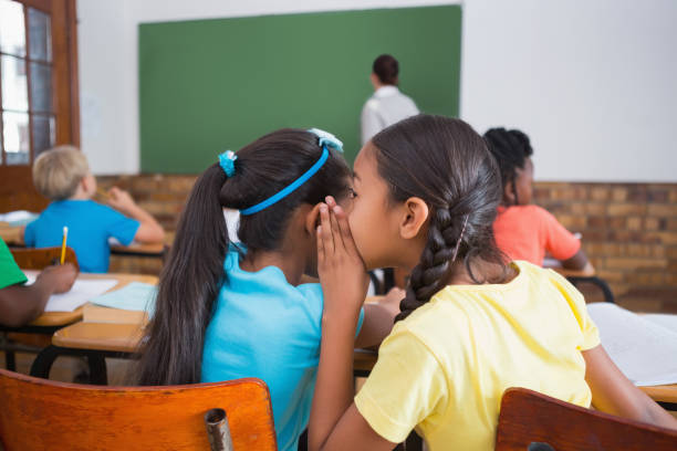 istock Cute pupils whispering in classroom 819189086