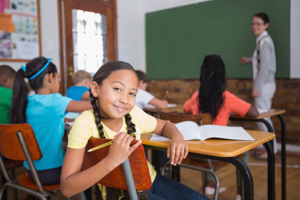 istock Cute pupil smiling at camera in classroom 819190186