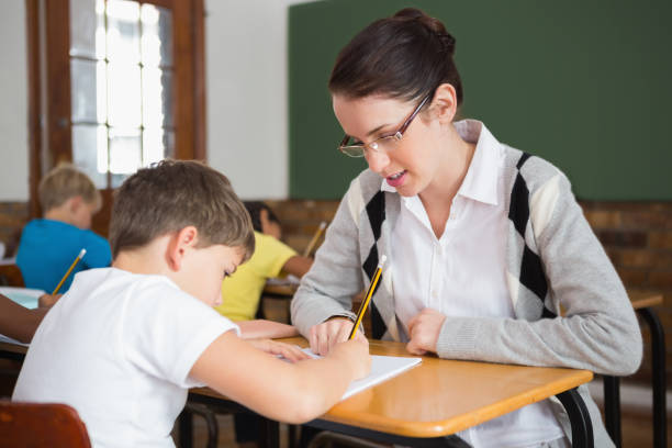 istock Pretty teacher helping pupil in classroom 819190436