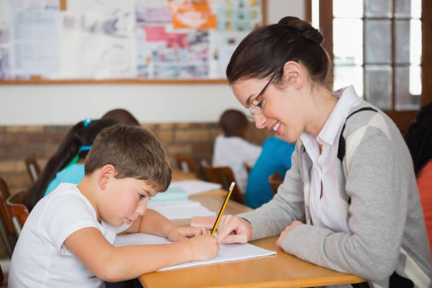 istock Pretty teacher helping pupil in classroom 819191176