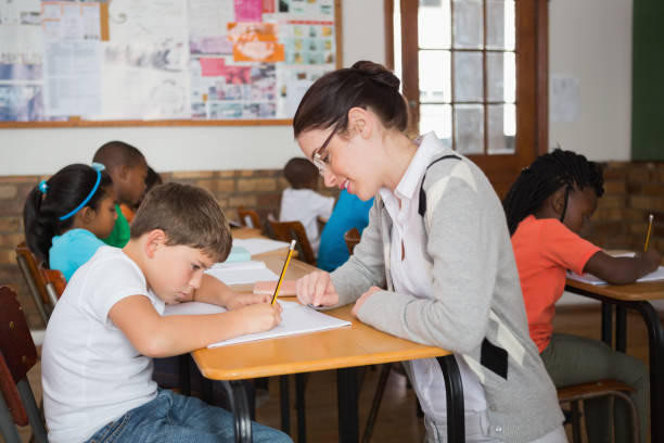 istock Pretty teacher helping pupil in classroom 819191312