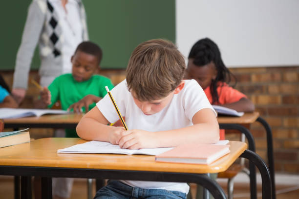 istock Cute pupils writing at desk in classroom 819191544