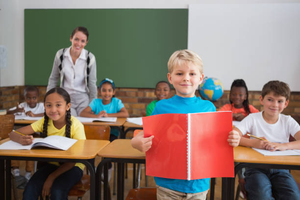 istock Cute pupils smiling at camera in classroom 819191788