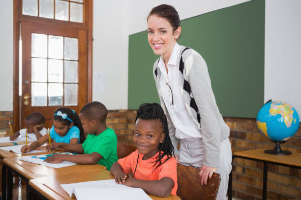 istock Cute pupil and teacher smiling at camera in classroom 819191890
