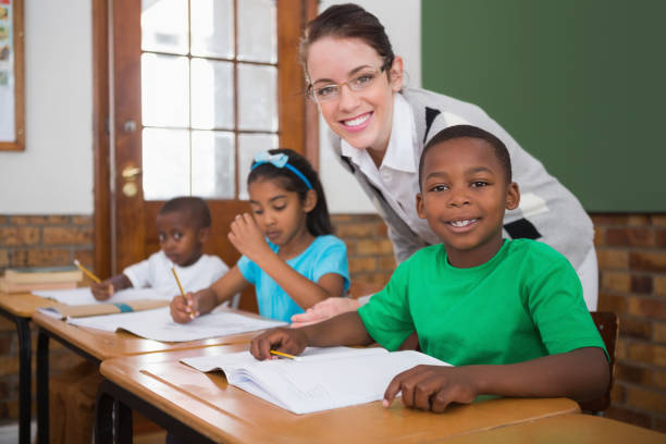 istock Pretty teacher helping pupil in classroom 819192132