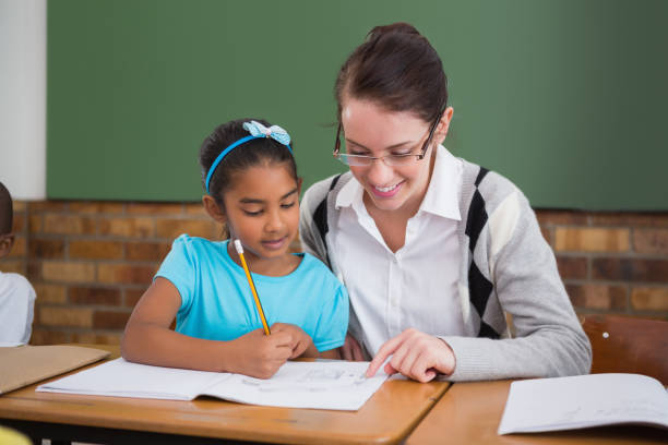 istock Pretty teacher helping pupil in classroom 819193188