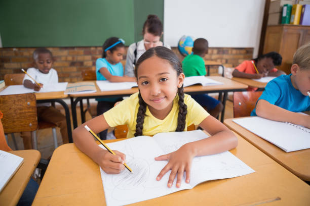 istock Cute pupils writing at desk in classroom 819197688