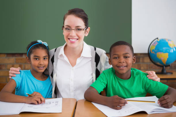 istock Cute pupils and teacher smiling at camera in classroom 819197838