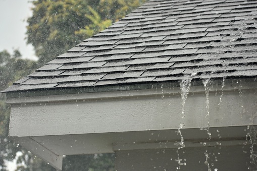 A photograph of rain pouring down a roof.