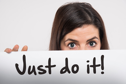 young woman holding a whiteboard written just do it on it motivation