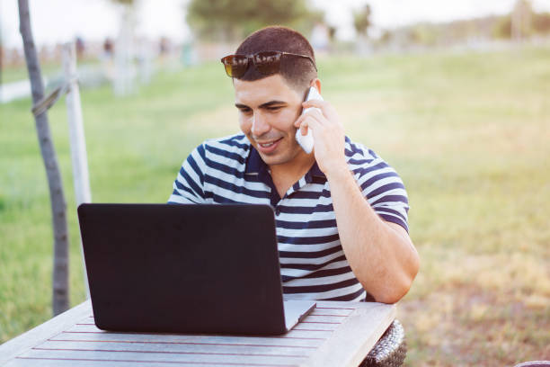 istock Young man talking on mobile phone and working on laptop in cafe 819223110