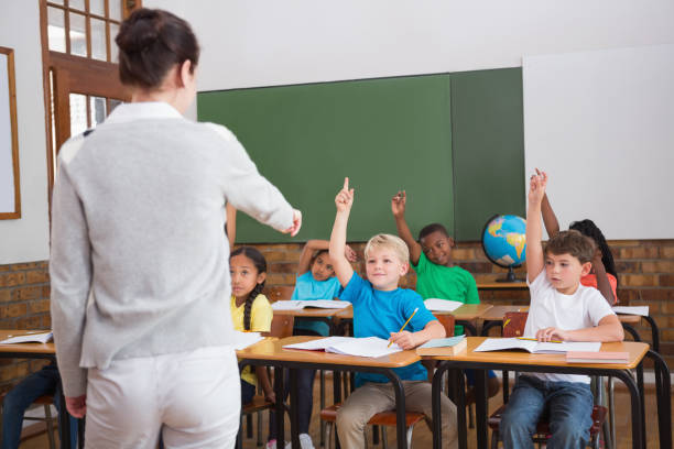 istock Cute pupils raising their hands in class 819225182