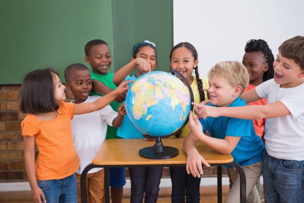istock Cute pupils pointing to globe in classroom 819227252