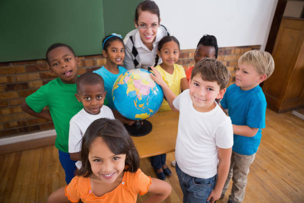 istock Cute pupils pointing to globe in classroom 819227264