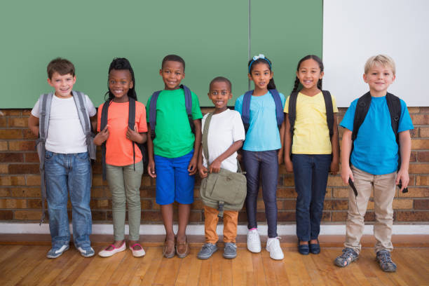 istock Cute pupils smiling at camera in classroom 819229290