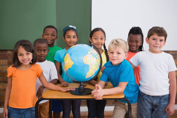 istock Cute pupils smiling at camera in classroom with globe 819232634