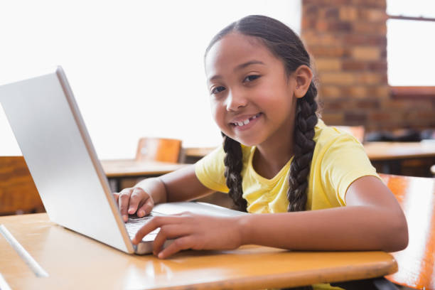 istock Cute little pupil looking at laptop in classroom 819233634