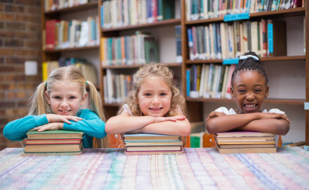 istock Cute pupils smiling at camera in library 819233894
