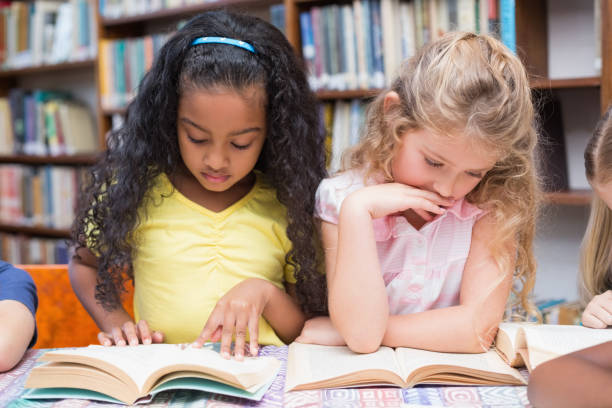 istock Cute pupils reading books in library 819234132