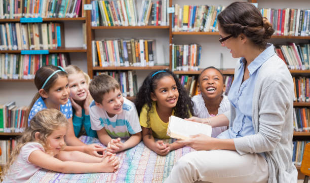 Cute pupils and teacher reading in library Cute pupils and teacher reading in library at the elementary school librarian stock pictures, royalty-free photos & images