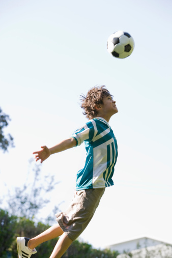 young boy en dirección una pelota de fútbol photo