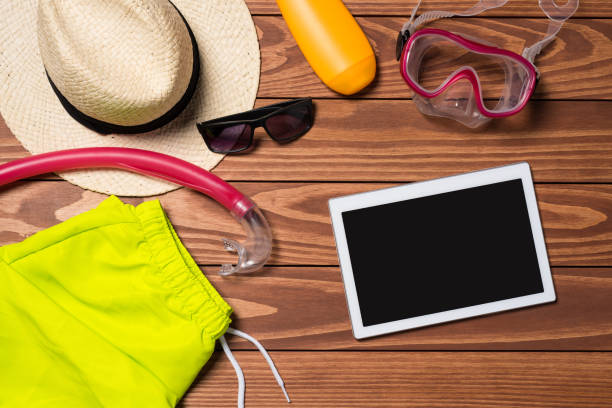 istock Summer accessories with white digital tablet on wooden table 819289980