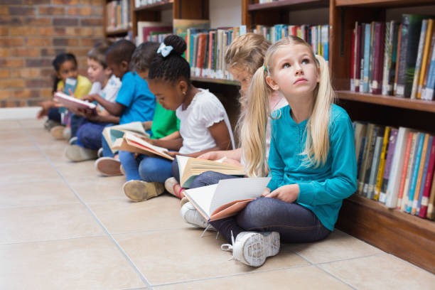 istock Cute pupils sitting on floor in library 819289986