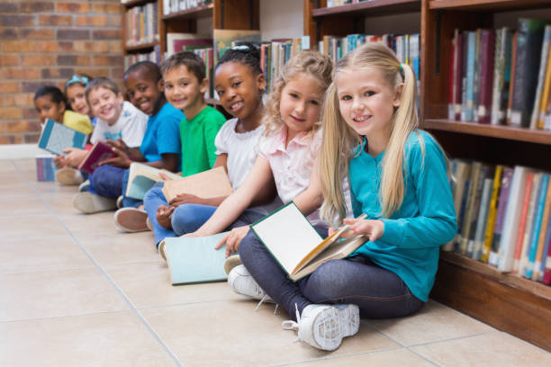istock Cute pupils sitting on floor in library 819290000