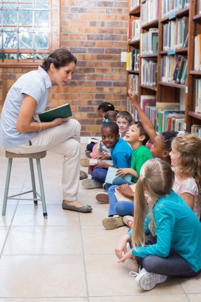 istock Cute pupils sitting on floor in library 819290024