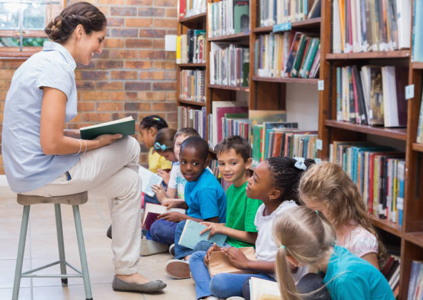 istock Cute pupils sitting on floor in library 819290038