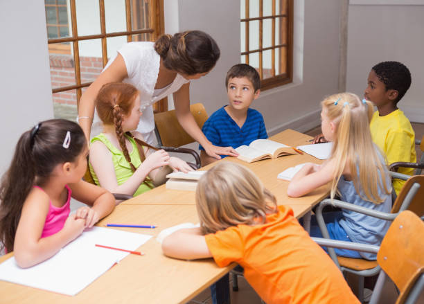 istock Pretty teacher standing with pupils at desk 819320668