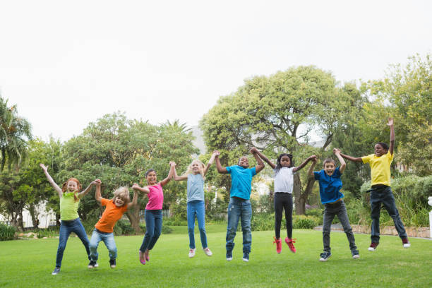 istock Cute pupils jumping on the grass outside 819321884