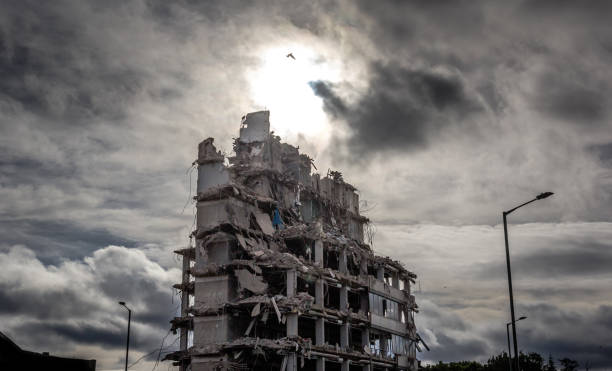 The End A part demolished office building is highlighted against a dramatic sky. the ruined city stock pictures, royalty-free photos & images