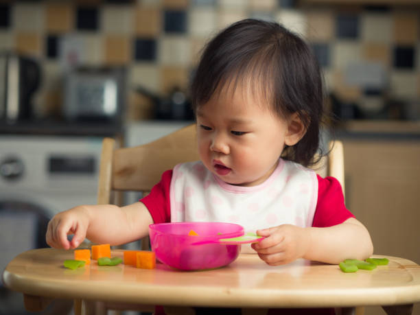 istock baby girl eating at home 819339914