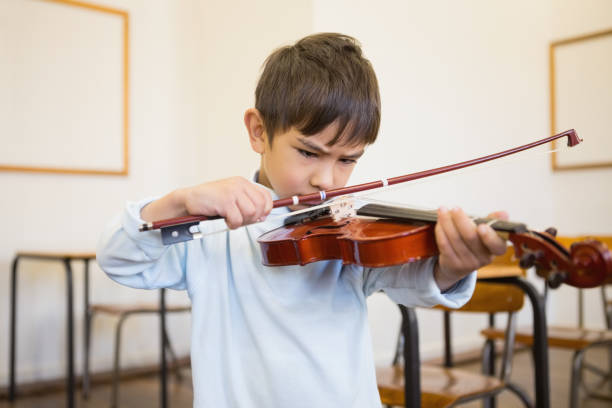 istock Cute pupil playing violin in classroom 819351628