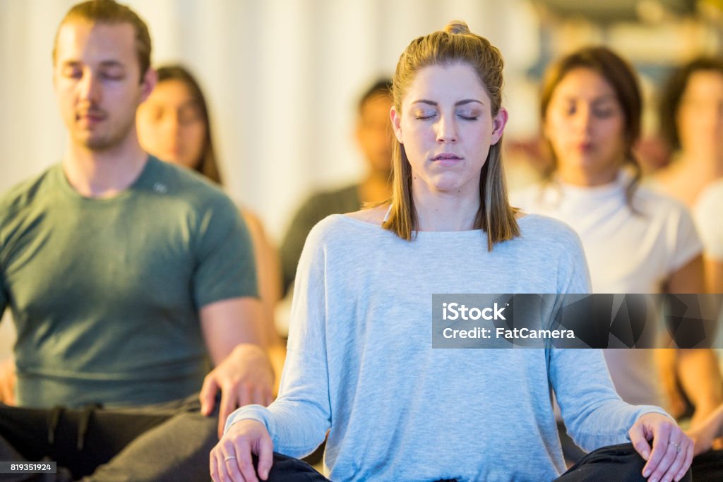 Meditation Class A multi-ethnic group is in a yoga and meditation class. In this frame the group is meditating while sitting indoors in the lotus position Group Of Objects Stock Photo