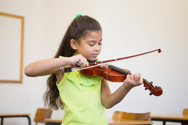 istock Cute pupil playing violin in classroom 819352328