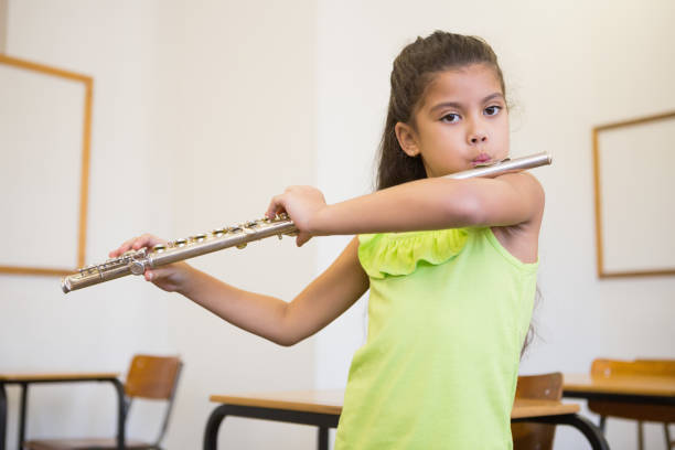 istock Cute pupil playing flute in classroom 819368004