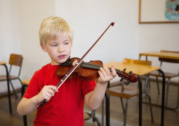 istock Cute pupil playing violin in classroom 819368042