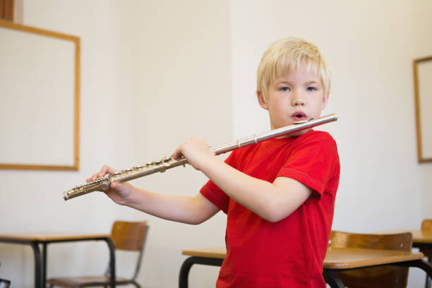 istock Cute pupil playing flute in classroom 819368132