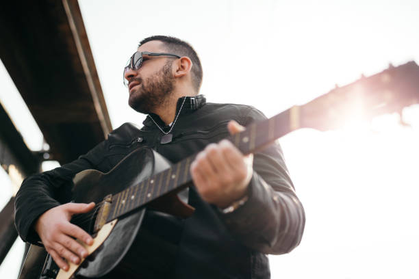 istock Young man playing guitar outdoors 819368298