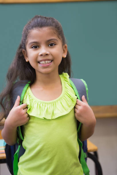 istock Cute pupil smiling at camera in classroom 819368430