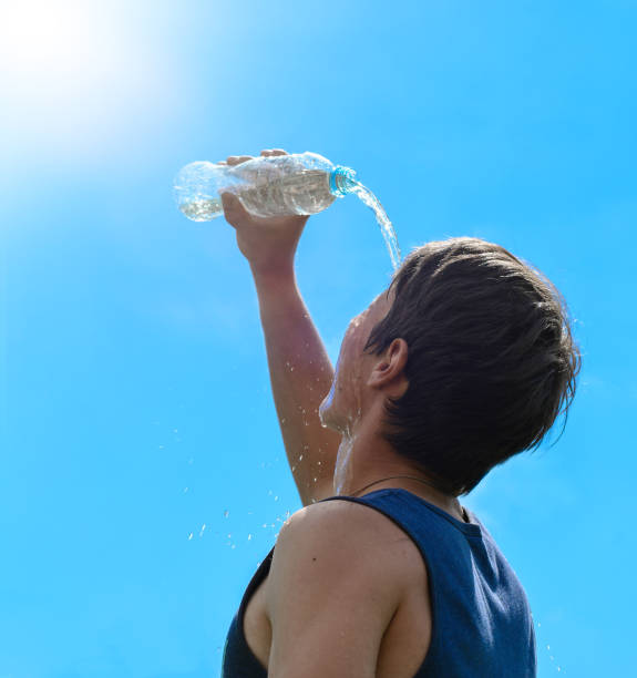 istock Young man splashing and pouring fresh water from a bottle on his head 819373358