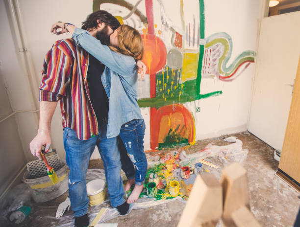 Young couple kissing and embracing while painting walls