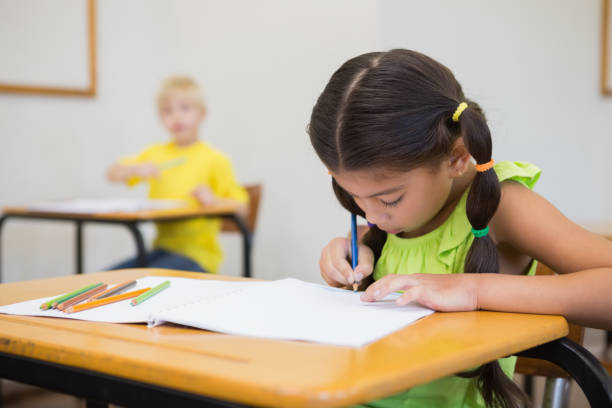 istock Cute pupils colouring at desks in classroom 819381948