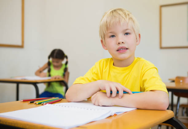 istock Cute pupils colouring at desks in classroom 819382058