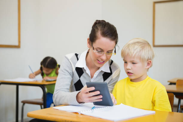 istock Pretty teacher helping pupil in classroom 819382220