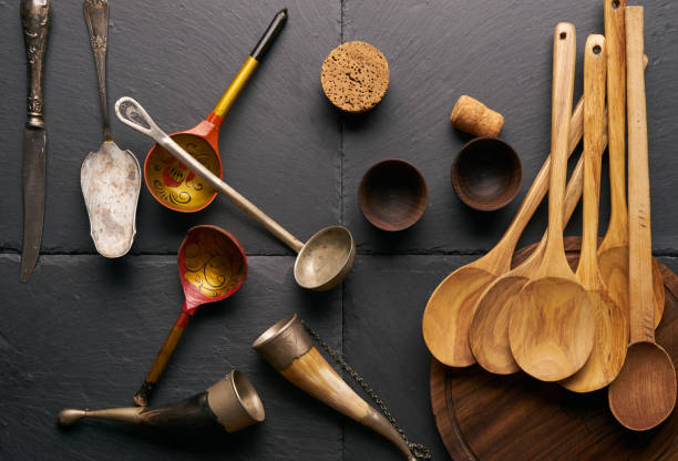 istock Various kitchen utensils wooden spoon round cutting board bower silver knife and spatula wooden bowls for sauce horn for wine on black stone background. 819382390