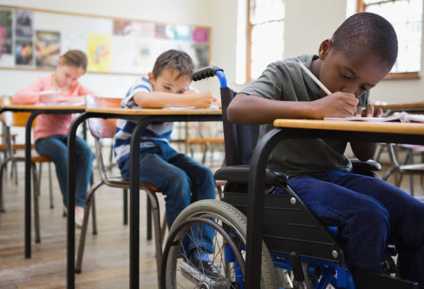 Cute pupils writing at desks in classroom