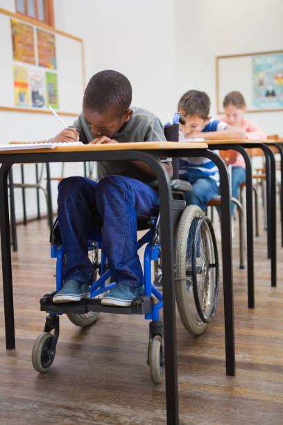istock Disabled pupil writing at desk in classroom 819382510